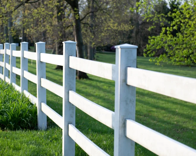 white wood fence of a field with some trees around